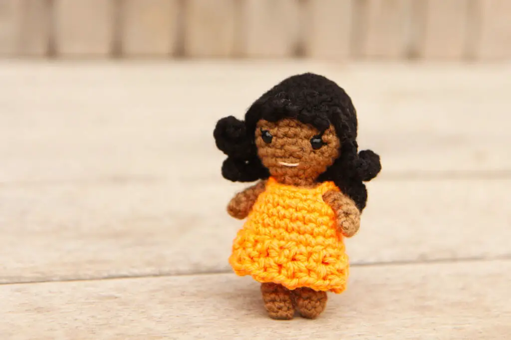 small crochet doll with wavy hair and a lacy party dress