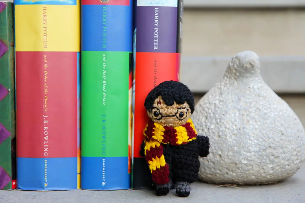 mini harry potter crochet doll standing in front of books
