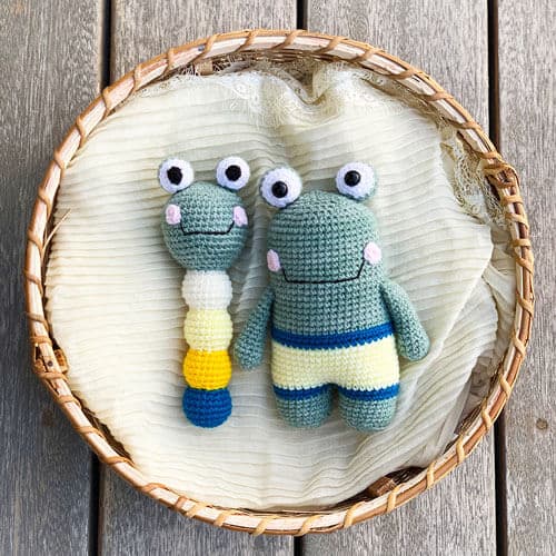 A crocheted frog rattle and toy in a basket