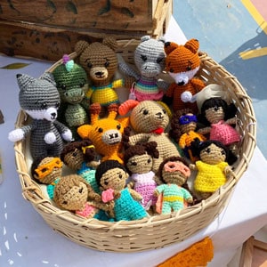 Small amigurumi dolls and animals in a basket at a craft market