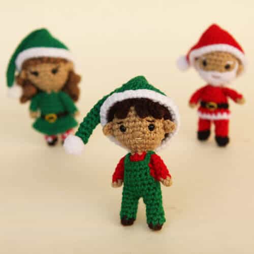 Boy amigurumi elf in the front with a girl crochet elf and a crochet santa in the back