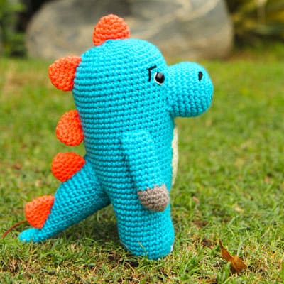 blue crochet dinosaur with orange spikes