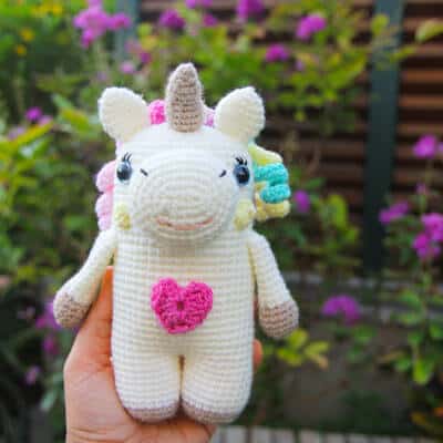 amigurumi unicorn with a heart on her belly and a colourful mane