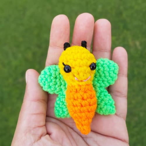 Small crochet butterfly with a yellow and orange body and green wings