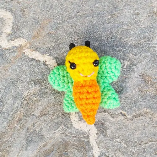 amigurumi butterfly with a yellow and orange body and green wings