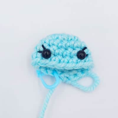 The beginning of a butterfly head crocheted with eyes inserted and eyelashes sewed on