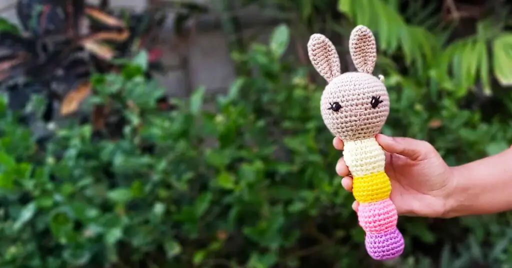 cute crochet baby rattle with a stem in purple, pink and yellow
