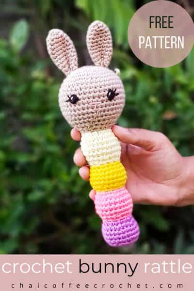 Bunny crochet baby rattle with long ears and a rattle stem in purple, pink, yellow, and lemon. The text overlay says crochet bunny rattle free pattern