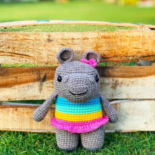crochet hippo in a rainbow dress with a pink bow in her hair