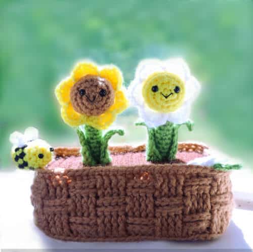 crochet flower pot with two crochet flowers and an amigurumi bee