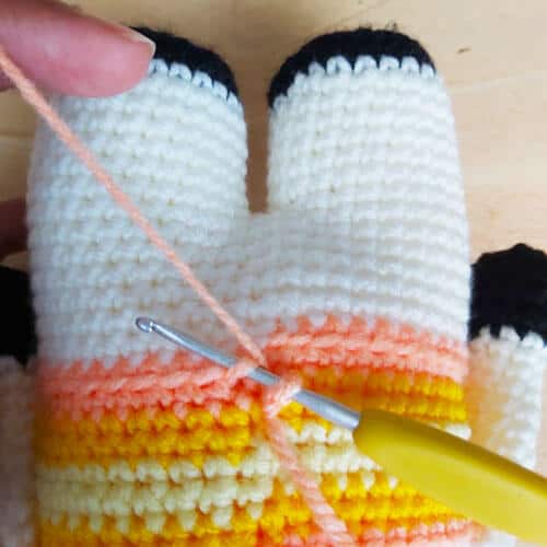 crochet hook inserted into front loops at the base of the tank top