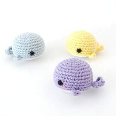 one piece amigurumi whales in blue, yellow and purple
