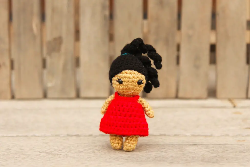 small crochet doll with ponytail and red sundress