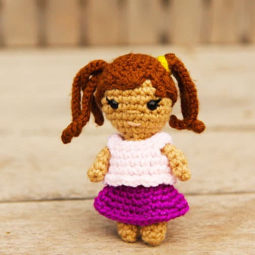 small crochet doll with pigtails and a skirt and blouse