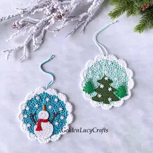 crochet ornaments with snowfall. one has a christmas tree and the other a snowman
