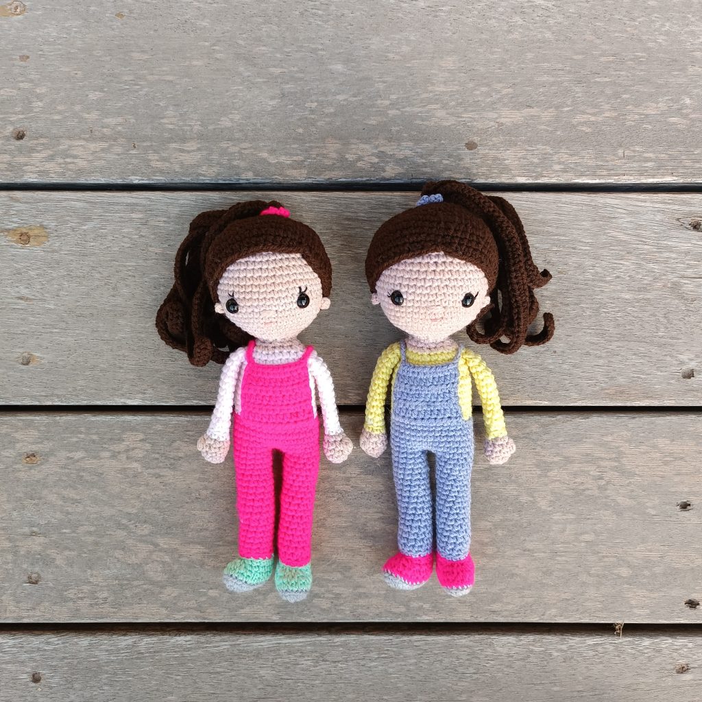 two crochet dolls wearing dungarees with ponytails