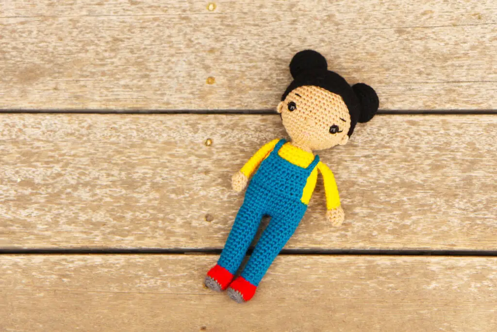 crochet doll with overalls and two hair buns