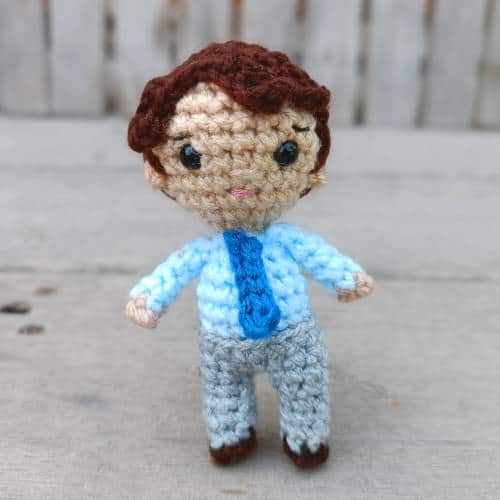 Crochet boy doll with gray pants, a light blue shirt, and a teal tie
