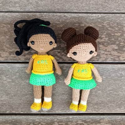 two crochet cheerleader dolls in green and yellow. One has a ponytail and the other two hair buns