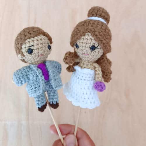 crochet bride and groom cake toppers for a wedding cake. The dolls have wooden sticks inserted into them to be put into a wedding cake