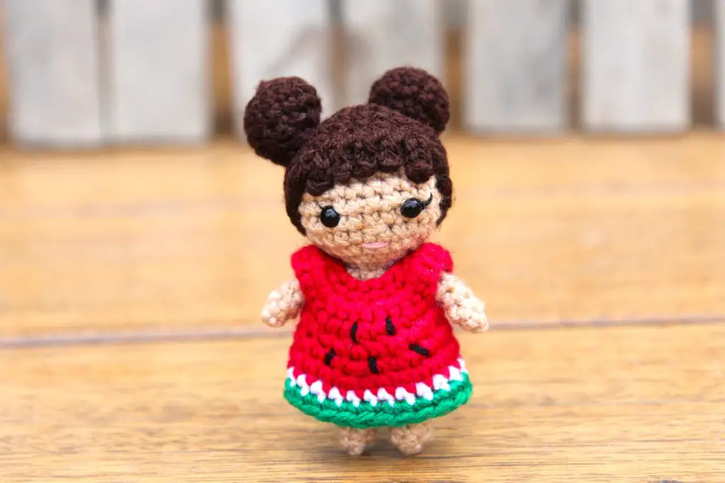 mini crochet doll with two hair buns and a watermelon dress