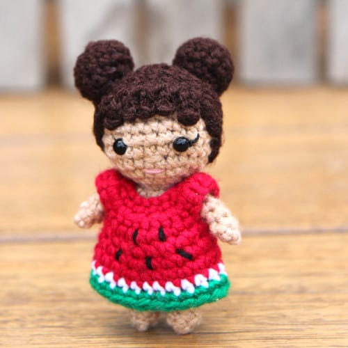 small crochet doll with two hair buns and a watermelon dress