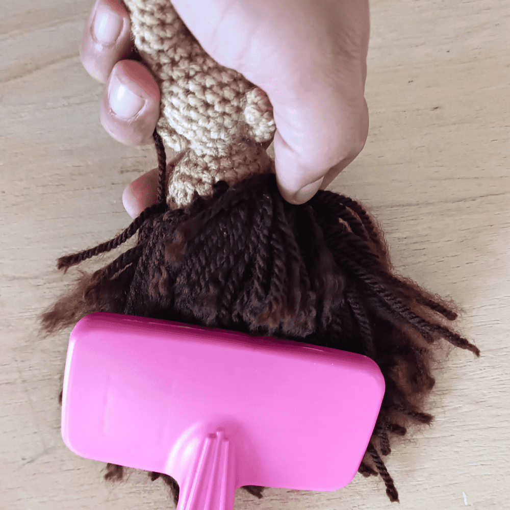the back of a doll's hair being brushed with a pet slicker