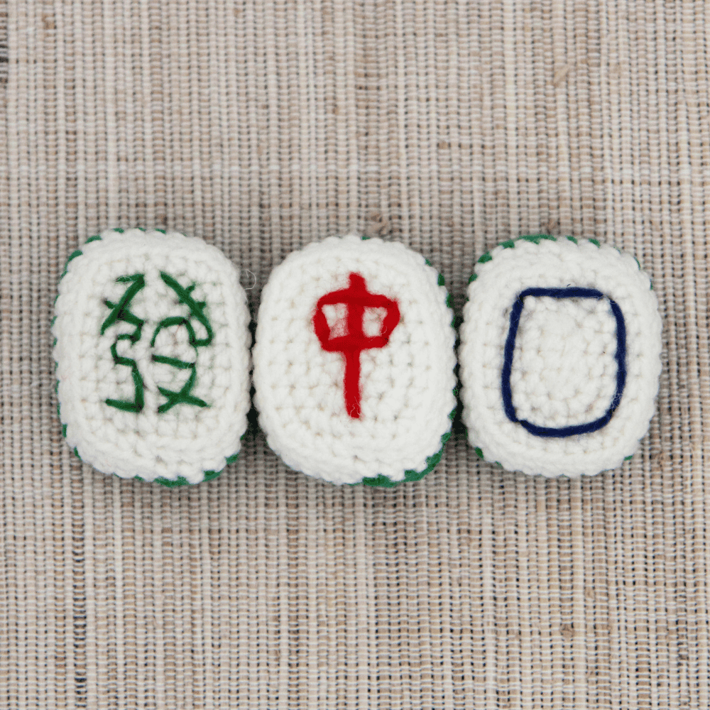 Three crochet mahjong dragon tiles: green dragon, red dragon, and white dragon